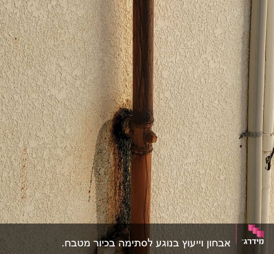 צינור חלוד על קיר עם סימני נזילה